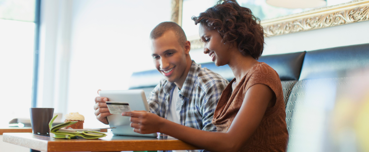 Couple in a cafe using a Scott Credit Union debit card to manage their high-yield checking account online.