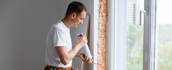 Homeowner sealing a window as part of high-efficiency home upgrades that can be financed with a Scott Credit Union HELOC.